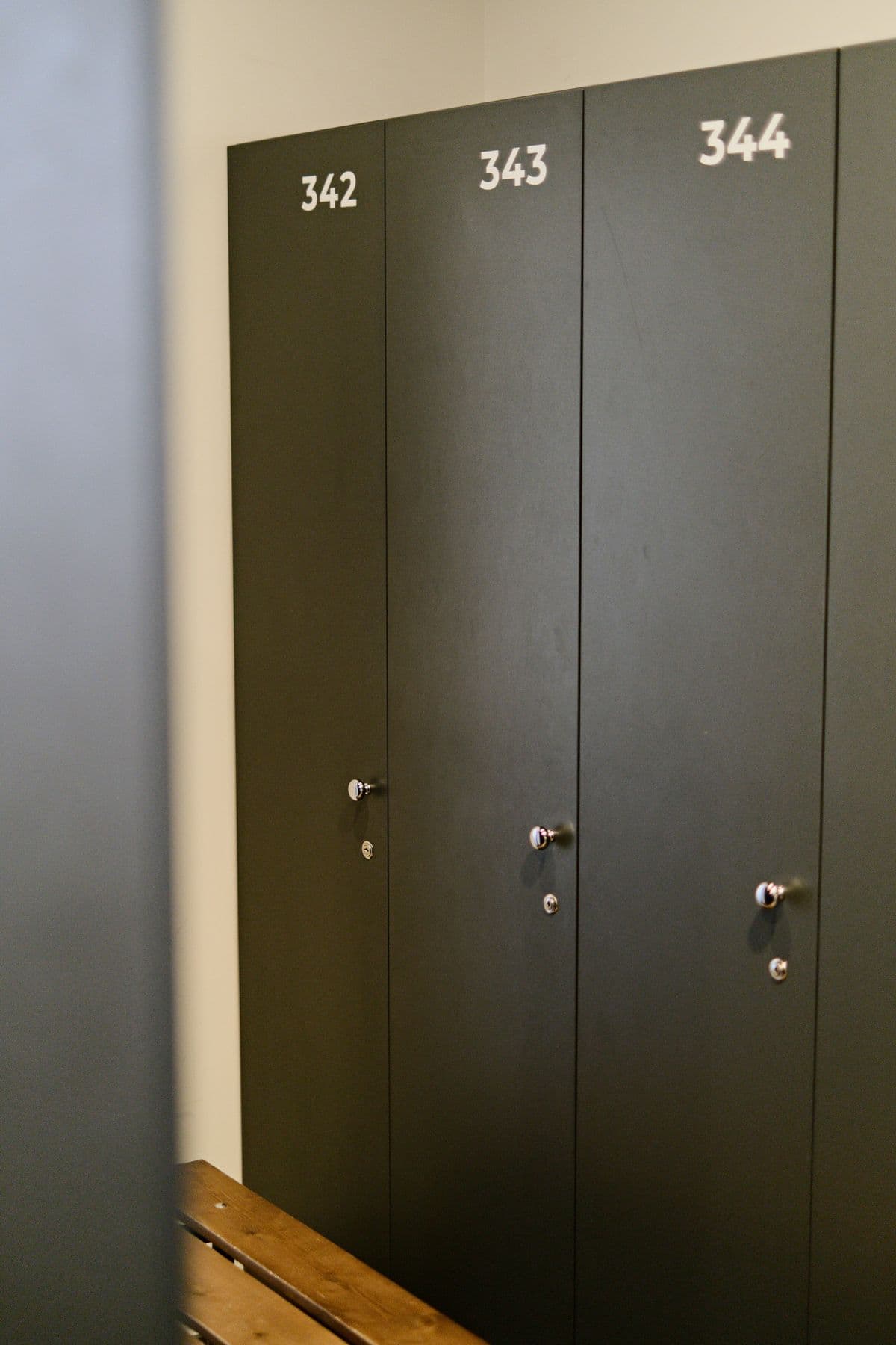 Numbered changing room lockers beside a wooden bench