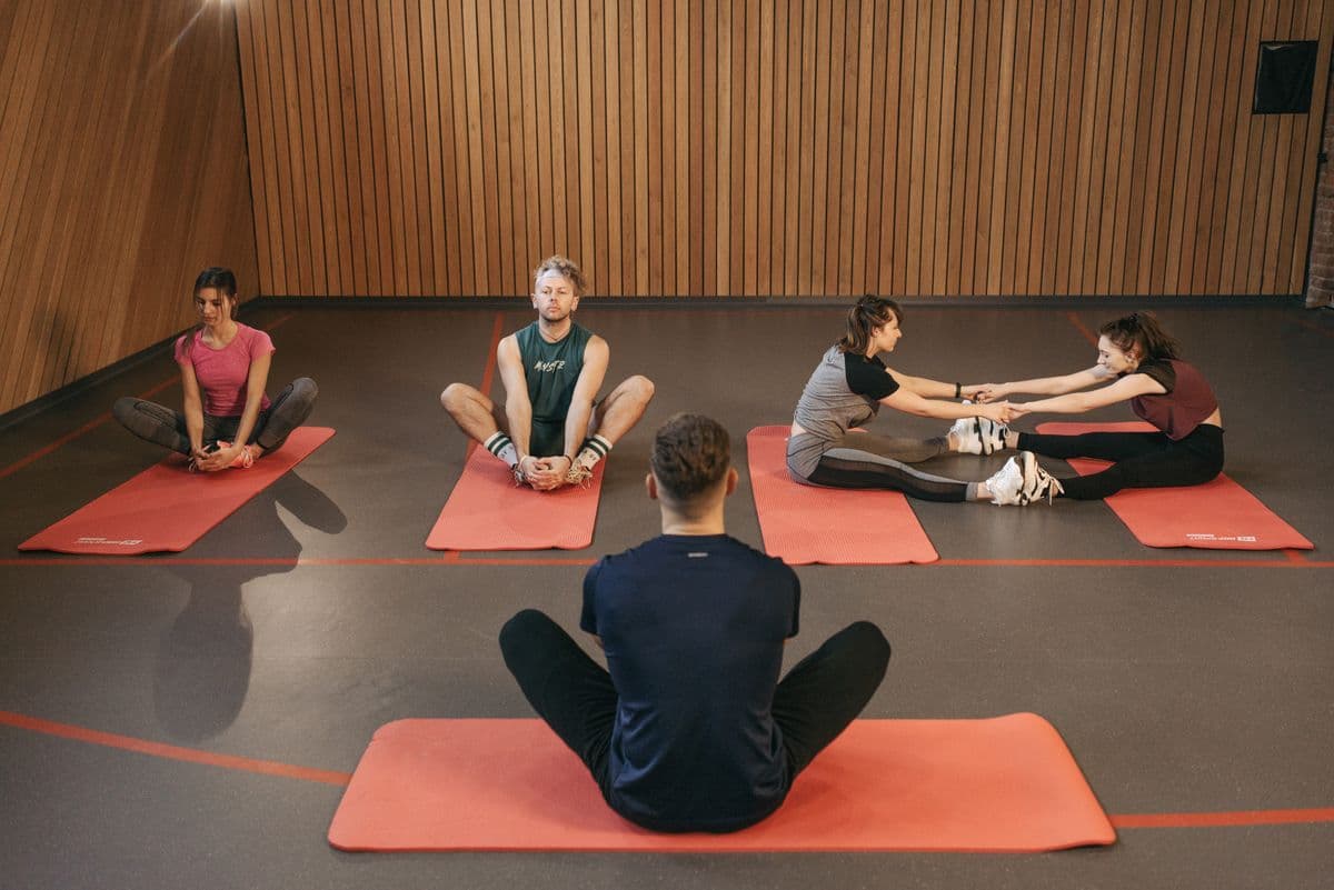 Trainer leading a seated stretch with members sitting on exercise mats