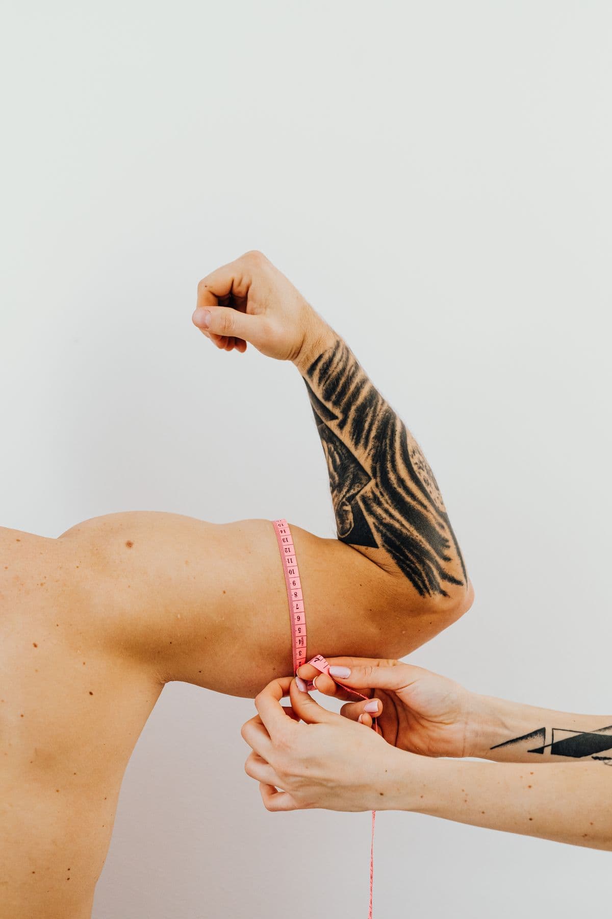 Coach measuring a member's arm with a tape measure to record progress